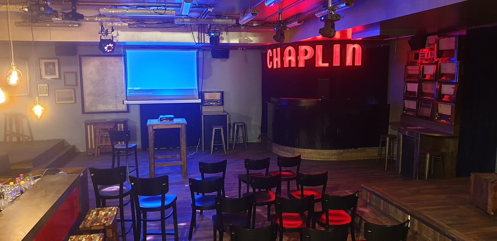 Raum mit Stühlen in einer Bar und eine Beamerprojektion an der Wand