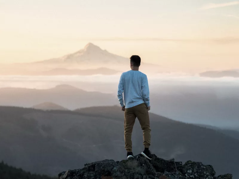 Mann auf einem Berg mit Nebel im Hintergrund