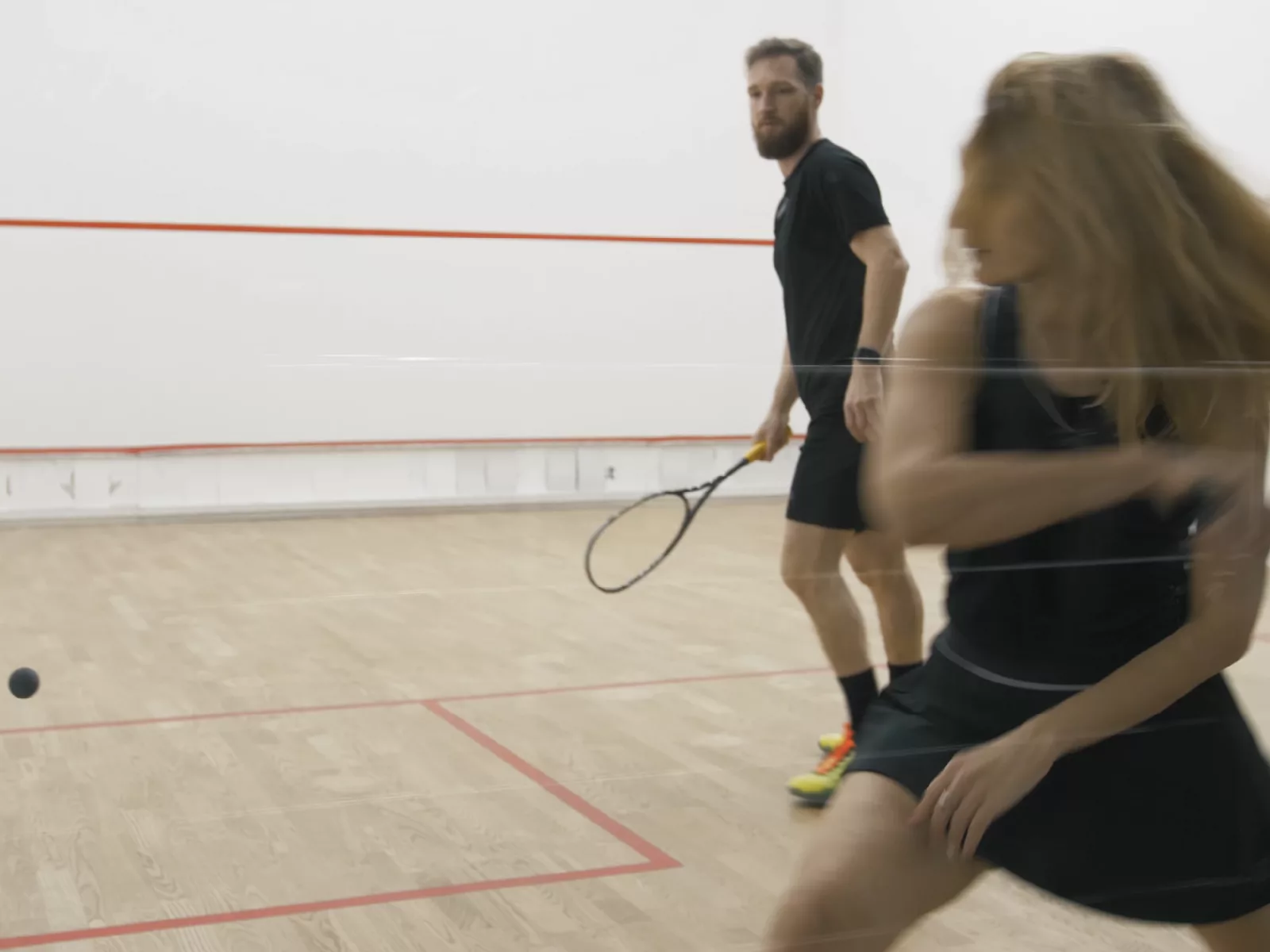 Ein Mann und eine Frau spielen in der Halle Badminton.