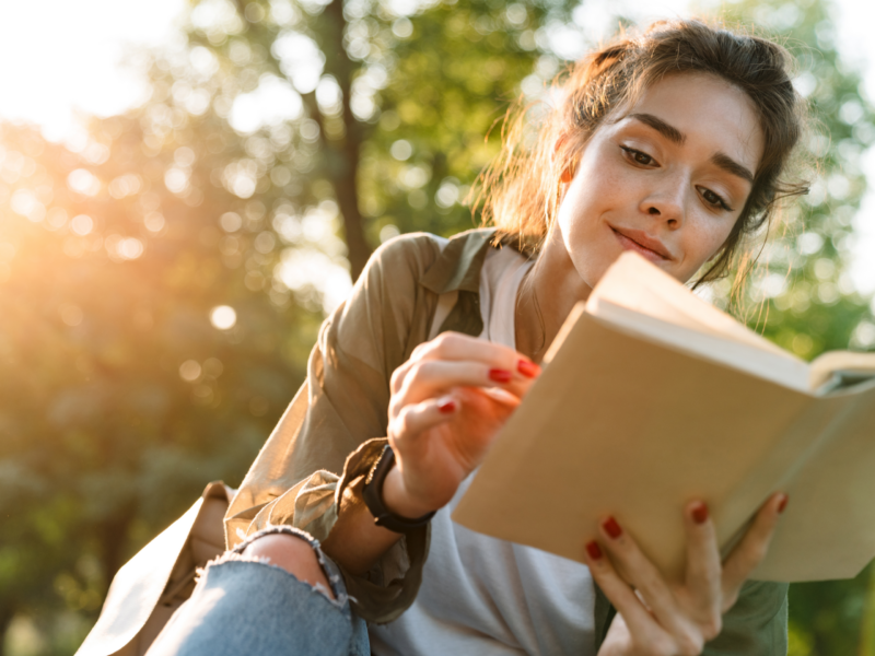 Junge Frau liest im Park in einem Buch